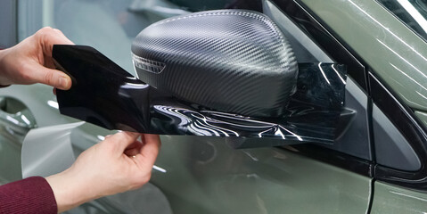 A car wrapping specialist applies a polyurethane film to the car. Selective focus. PPF protective...