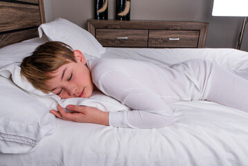 Male child in white pajamas sleeping in bed