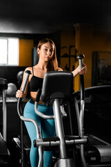 Fototapeta na wymiar Fitness girl doing cardio training in the gym on the orbitrek simulator