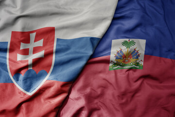 big waving national colorful flag of haiti and national flag of slovakia .
