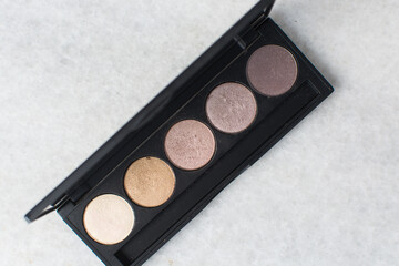 Overhead view of nude and brown eyeshadow palettes, nude themed eyeshadow palette on a marble table	