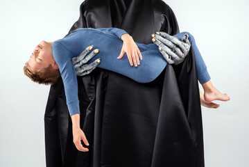 Young sleeping boy being carried away by a scary nightmare monster in black robes