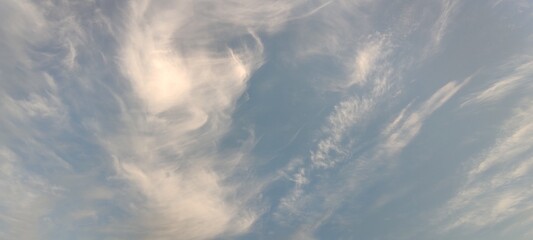 High cirrus clouds. Bright summer sky. High, semi-transparent cirrus clouds spread across the sky. Clouds of gray and white. They fill almost the entire space and the blue sky is visible through them.