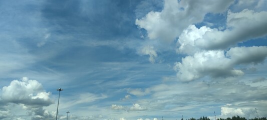 Clouds at different levels. Bright summer sky. High, semi-transparent cirrus clouds and low cumulus clouds spread across the sky. Clouds of gray and white colors of different shapes and sizes.