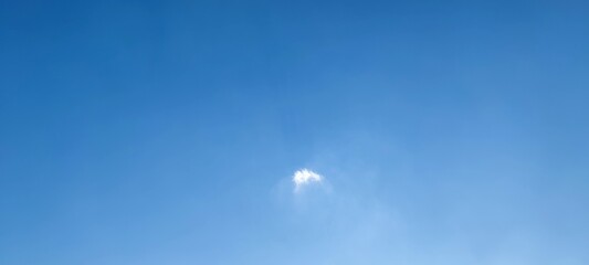 Lonely cloud in the sky. Summer sunny day, a small white fluffy cloud hangs in the light blue sky. Like a stroke of genius and a small flaw on a flawlessly clean canvas.