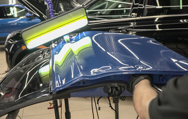 Process of paintless dent repair on car body. The mechanic at the auto shop with tools to repair...