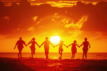 Orange-yellow silhouettes of five people holding hands running together in front of the board. Sunset background © panu101