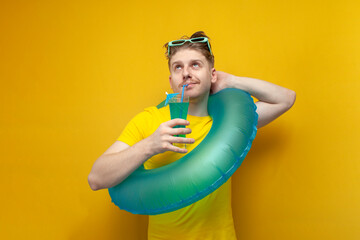 young guy in the summer on vacation with swimming inflatable ring drinking a refreshing blue...