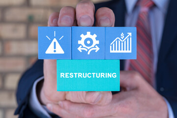 Businessman holding styrofoam blocks sees word: RESTRUCTURING. Concept of restructuring business...