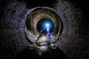 Foto op Canvas Dirty sewage flowing in round underground sewer tunnel © Mulderphoto