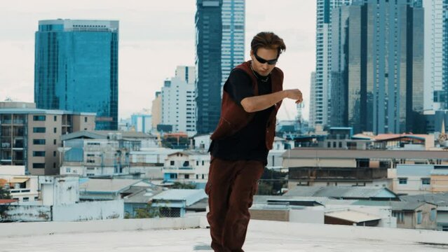 B-boy dance performance by professional street dancer at rooftop with sky scrapper, city view. Attractive asian hipster show energetic footstep. Active break dance. Outdoor sport 2024. hiphop.