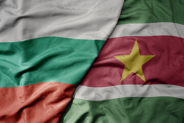 big waving national colorful flag of suriname and national flag of bulgaria .