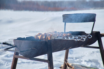 Barbecue meat on the grill on the fire in the open air. Russia. Winter.