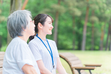 公園で話す高齢者と笑顔の介護スタッフの女性(話す・楽しい)
