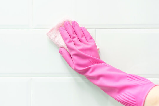 Female hands in pink glove holds rag on white background, spring cleaning concept.