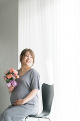 花束・ブーケを持つ妊婦・マタニティフォト（椅子に座る）

