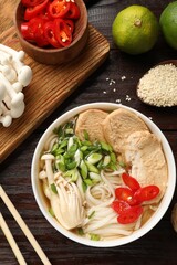 Delicious ramen with meat and ingredients on wooden table, flat lay. Noodle soup