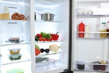 Modern open refrigerator full of different products