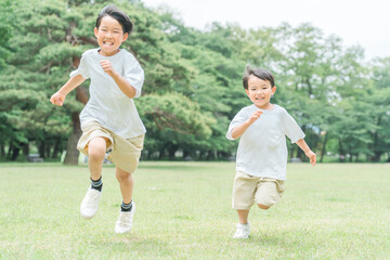 公園で追いかけっこする活発な子供達・兄弟・走る・短距離走

