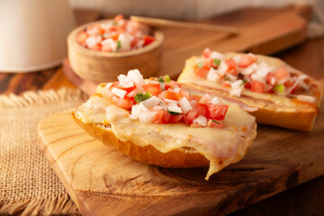 Molletes. Mexican recipe based on bolillo bread split lengthwise, spread with refried beans and gratin cheese, adding pico de gallo sauce and some protein such as ham, bacon or chorizo.