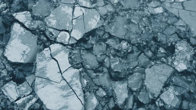 Flying over thick ice on top of a frozen lake during the middle of winter.