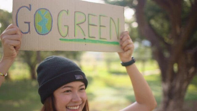 Go green Gen Z woman asia young people smile looking at camera showing save the earth planet world care banner poster sign in city nature tree public park. Protect future asian hope net zero waste.
