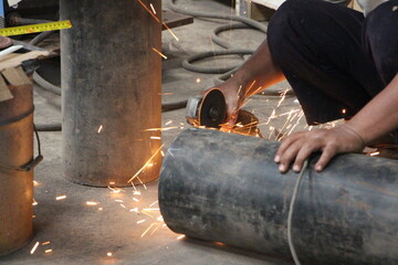 Workers full of sparks, without wearing uniform without gloves, use grinda smoothing out the remains of rough cuts