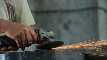 Workers full of sparks, without wearing uniform without gloves, use grinda smoothing out the remains of rough cuts