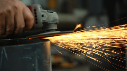 Workers full of sparks, without wearing uniform without gloves, use grinda smoothing out the...
