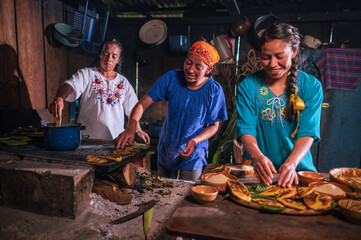 Obraz na płótnie Canvas Latin women enjoy preparing sweet tamales and cooking them in a clay pan.