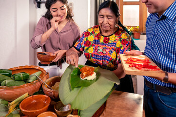 Beautiful Latin girl in the company of her grandmother and her boyfriend, make corn tamales for the...