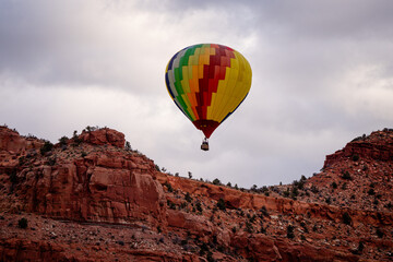 hot air balloon floating over southern Utah desert and cloudy skies