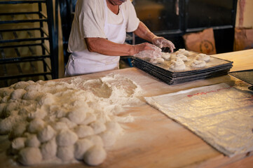Latin baker places raw bread on a tray.