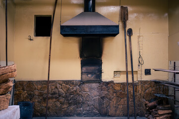 Front view of a handmade oven with wooden instruments around it.