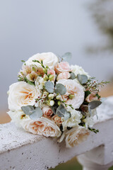 An elegant bouquet with blooming white roses and delicate blue flowers rests on a stones railing. Concept for wedding arrangements, floral designs, or romantic events.