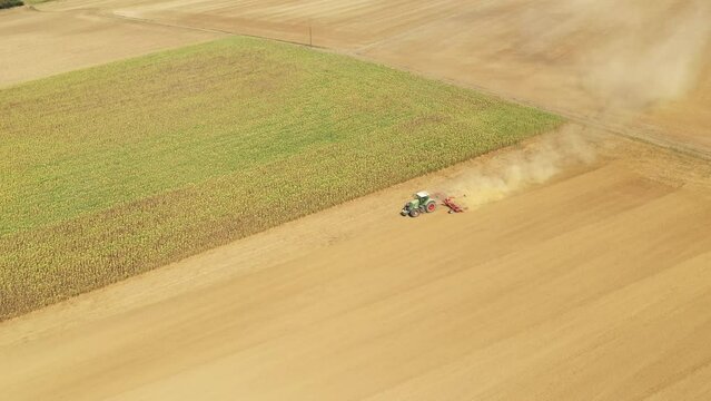 A tractor plows a barren field in the middle of the French countryside in Europe, France, in the summer on a sunny day.