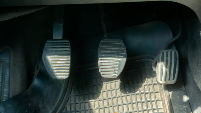 Close-up view showing the brake clutch and accelerator pedals in a vehicle, old used car. Generic view of car pedals, driving manual simple abstract concept, nobody, learning to drive symbol, European