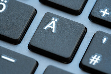 A macro shot showcasing the Ä with diaeresis key button on a black computer keyboard, with...