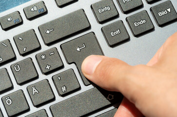 Finger pressing the enter key on a sleek, modern design keyboard, confirmation, command execution,...