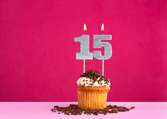 Birthday celebration with candle number 15 - Chocolate cupcake on pink background
