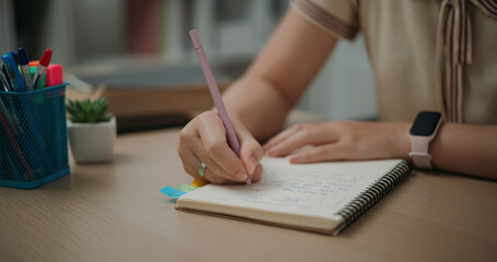 Selective focus, Hands of Female writer sitting at desk holding pen making notes in diary at home,...