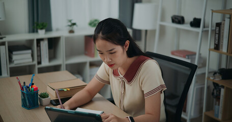 Selective focus, Side view, Female writer sitting at desk thinking idea holding pen making notes in...