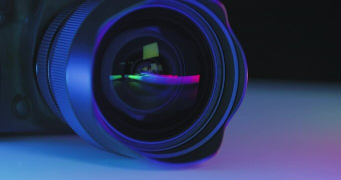 colorful play of colors is reflected in wide lens of photo camera lying on table, cinematic shot