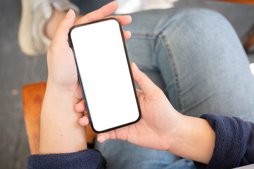 A woman using her phone while relaxing in a cafe. A smartphone white-screen mockup in a woman's hand