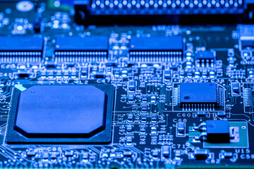 computer circuit board with chips and different electronic components. toned blue. closeup view.