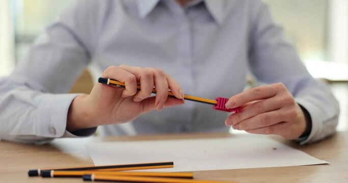Woman sharpens pencil with sharpener working in office