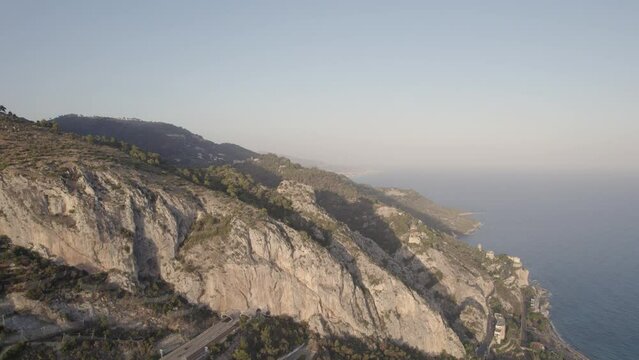 French Italian border Maritime Alps mountain range going into the Mediterranean Sea with car tunnel below, Aerial rising shot