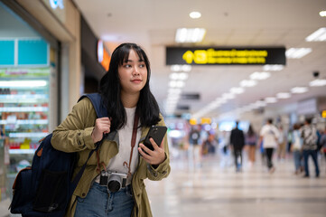 A female solo traveler or backpacker is walking in the airport, looking for her check-in counter.