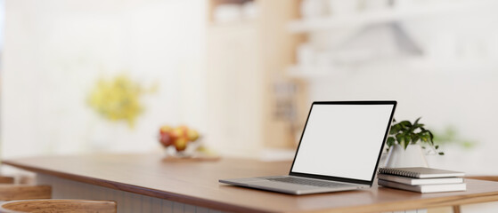 A laptop computer mockup on a wooden kitchen island tabletop in a modern bright kitchen.