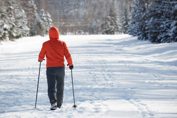 Senior Japanese man nordic walking along a rural winter road